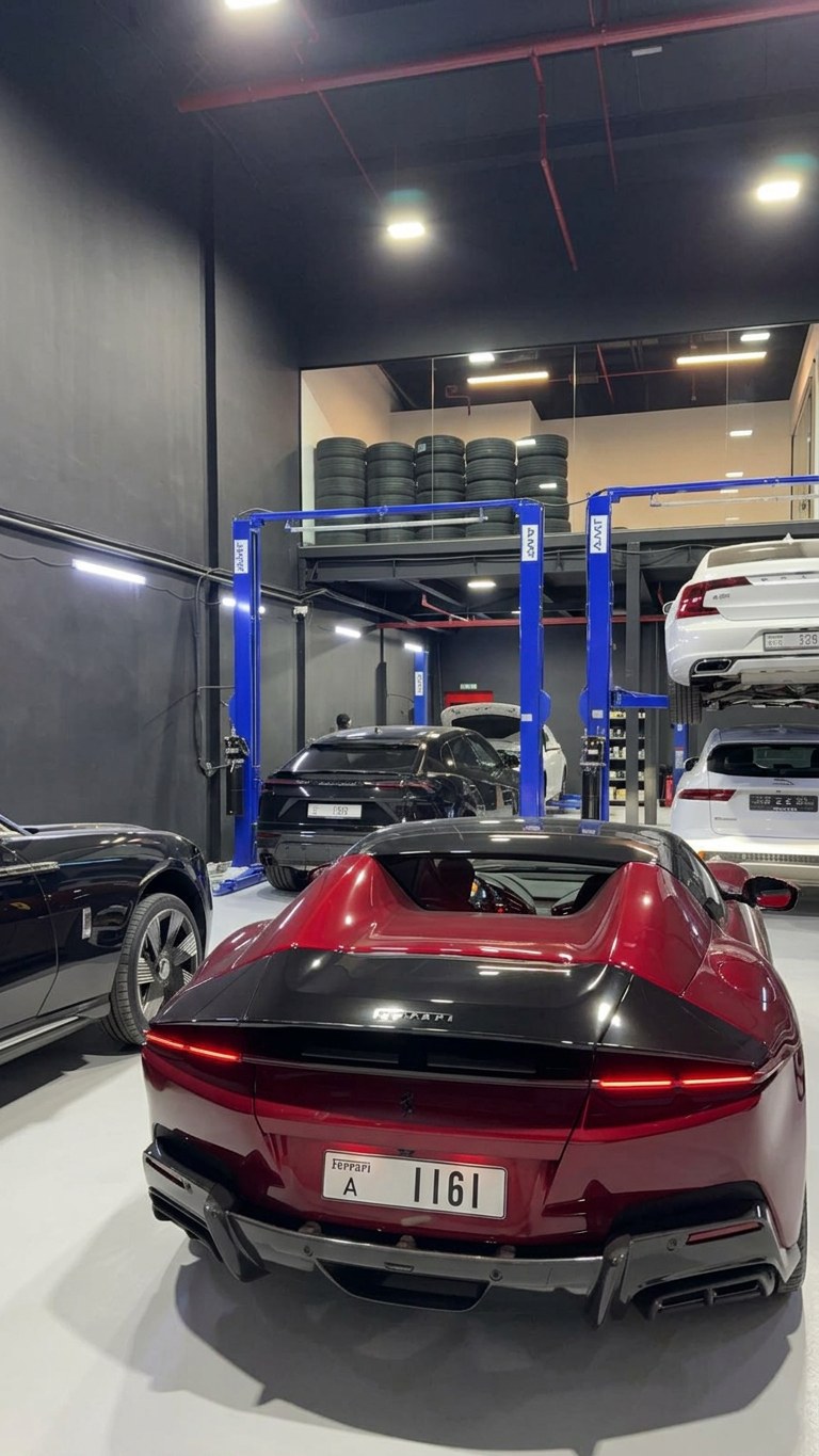 Satin red Ferrari Roma parked beside a Lamborghini Urus at the BRITFIX workshop