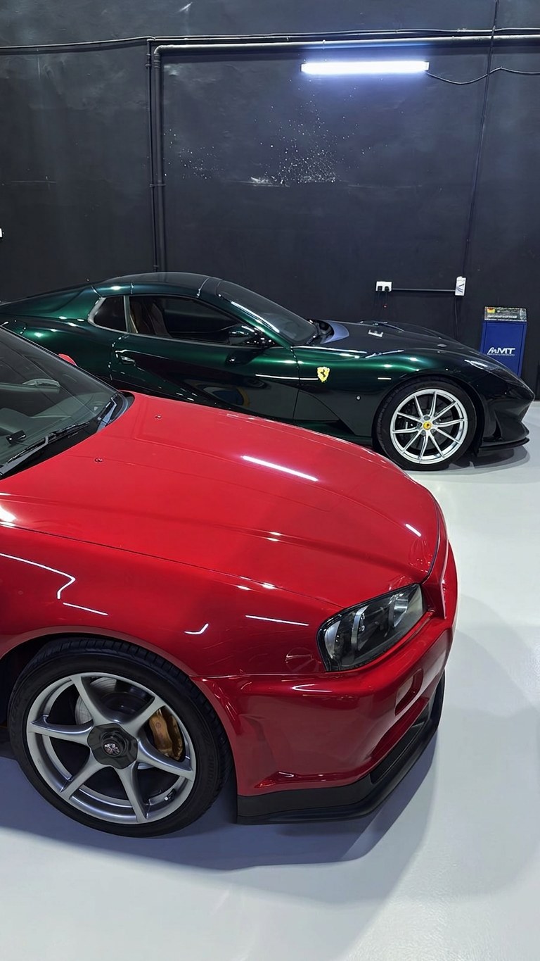 Green Ferrari 812 and red Nissan Skyline GT-R R34 at the BRITFIX workshop