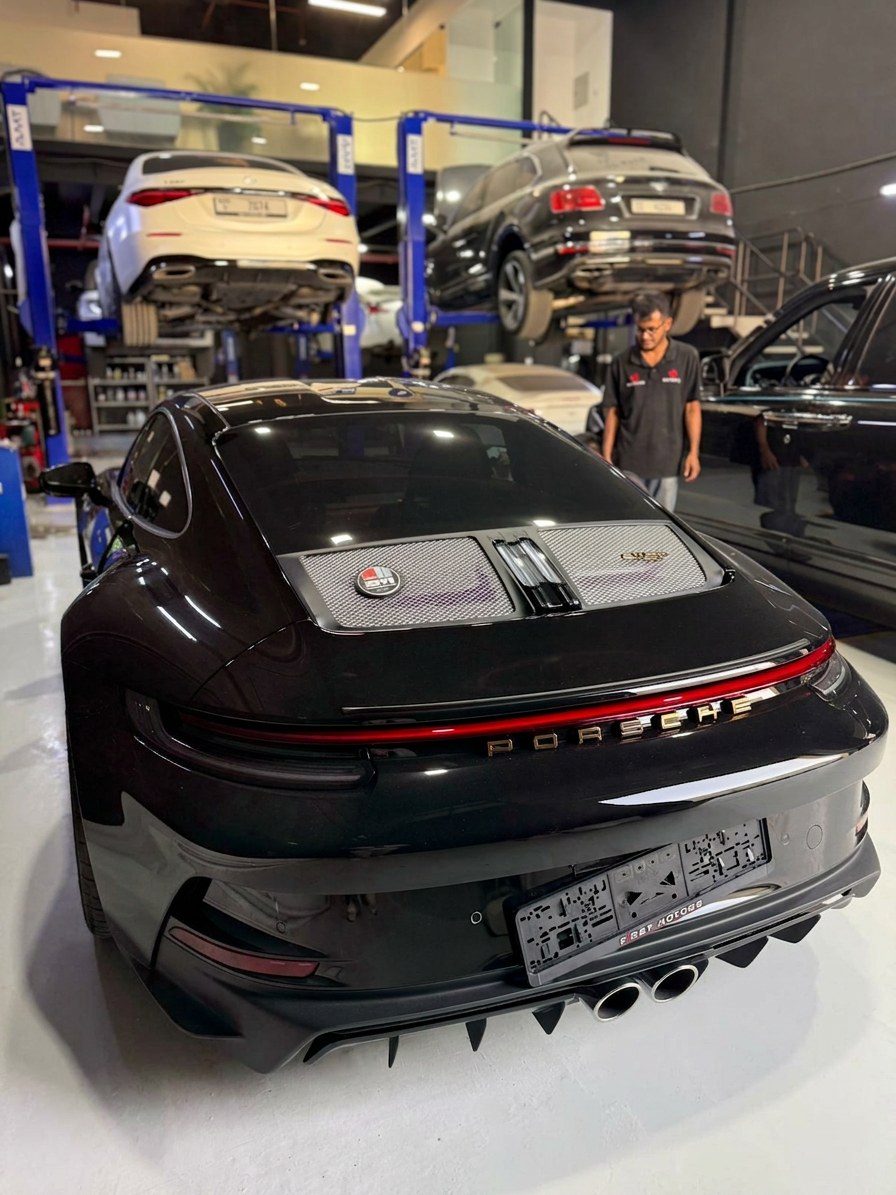 Black Porsche 911 GT3 in for service with a Bentley Bentayga and Mercedes on lifts behind